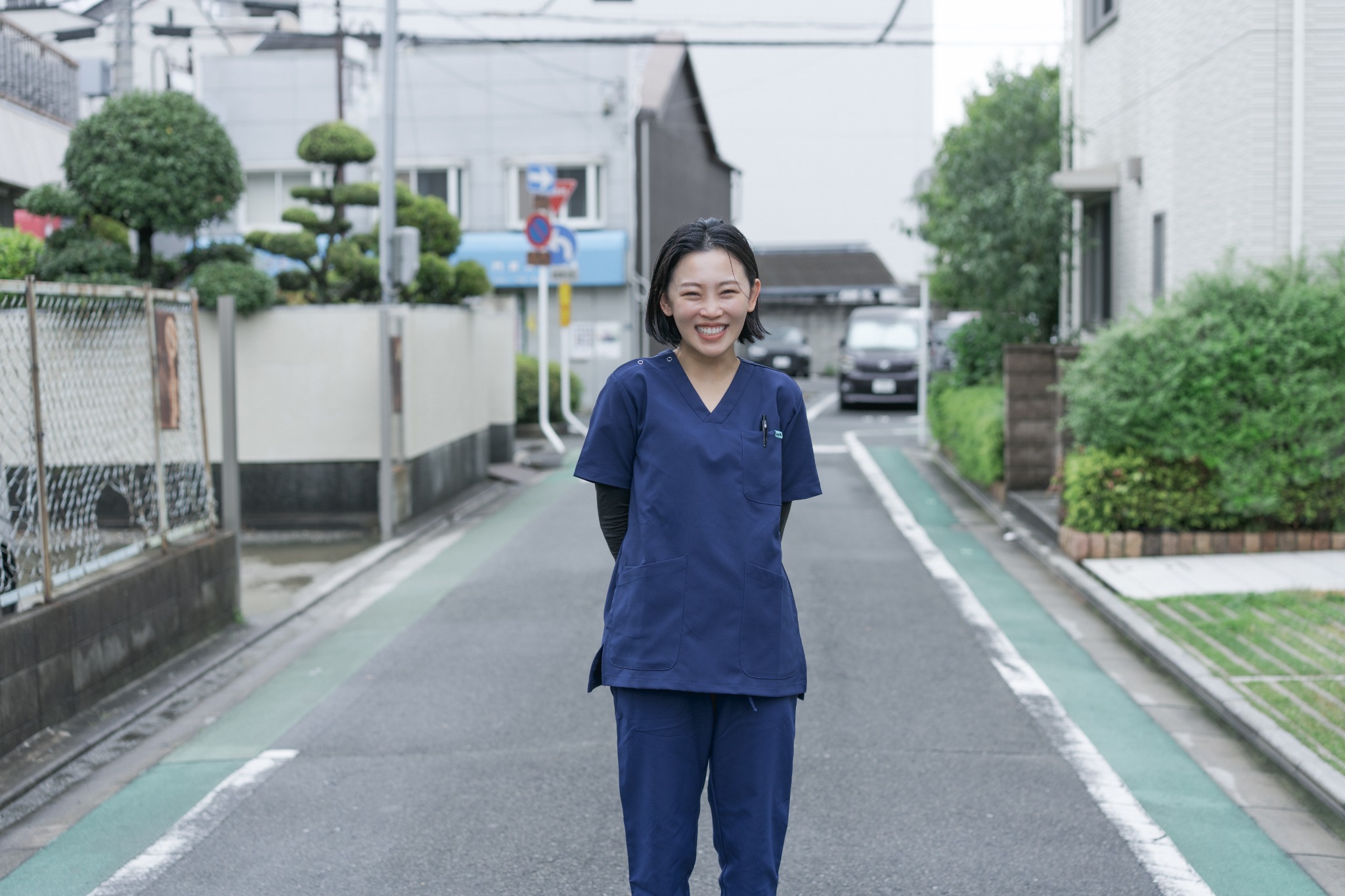 事務所前の道に立つ、笑顔の職員